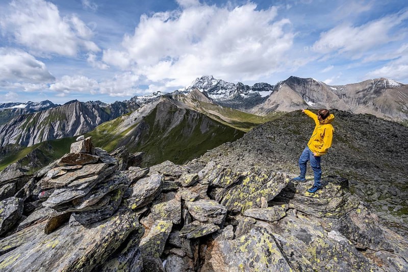 Mountaineer points into the distance, at the summit of Kastenegg, view of picturesque mountain landscape with snow-covered summit of the Großglockner, Wiener Höhenweg, Schober group, Hohe Tauern National Park, Carinthia, Austria, Europe