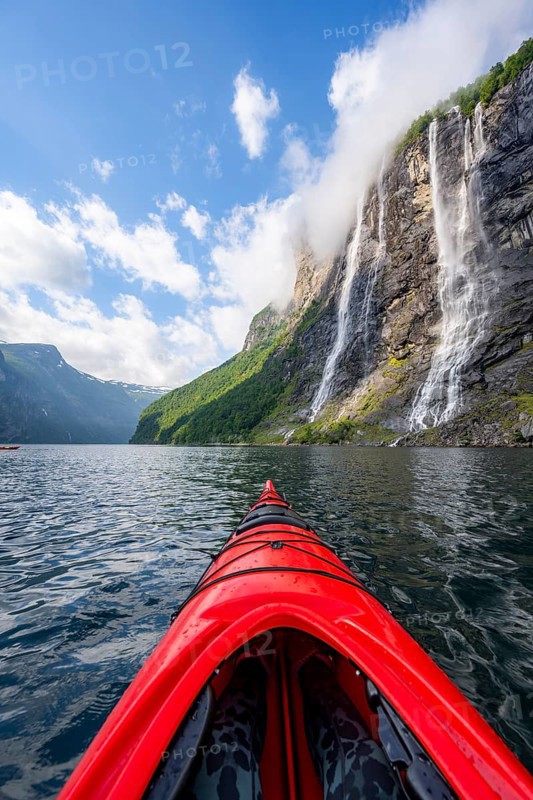 Kayak trip on the Geirangerfjord at the waterfall The Seven Sisters, tip of a red kayak in the fjord, atmospheric fjord landscape, first person view, near Geiranger, Møre og Romsdal, Norway, Europe