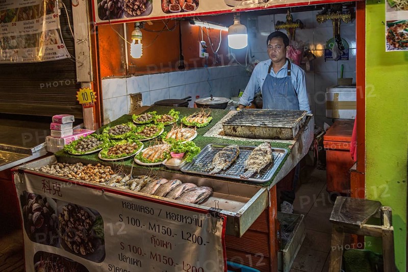 Thai street vendor offers fresh cooked seafood at the night market in downtown Chiang Rai, Thailand, Asia