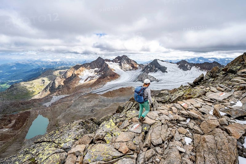 Mountaineer with helmet on a rocky hiking trail, in high mountain landscape, view of blue glacial lakes, mountain peaks Königshofspitz and Hofmannspitze with glacier of the Übeltalferner, Stubai Alps, South Tyrol, Italy, Europe