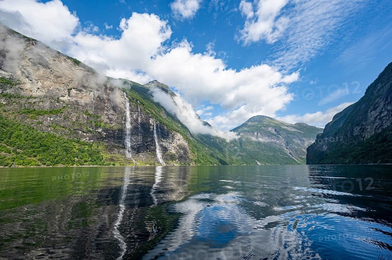 Atmospheric fjord landscape with waterfall The Seven Sisters, Geirangerfjord with reflection, Møre og Romsdal, Norway, Europe