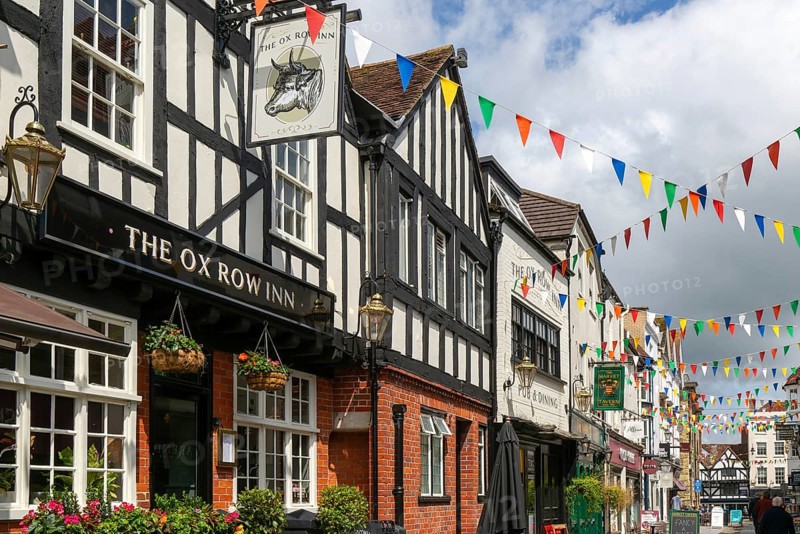Bunting flags decorating buildings in historic street, The Ox Row Inn and shops, Butcher Row, Salisbury, Wiltshire, England, UK