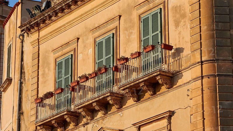 Detail of the façade of a historic building in warm sunlight with balconies, Ortigia Island, Isola di Ortigia, Historic Centre, Syracuse, Sicily, Italy, Europe