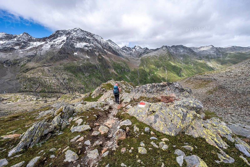 Mountaineer on a hiking trail, rocky mountain landscape, mountain peak Roter Knopf with fresh snow in summer, descent from the Hornscharte on the Wiener Höhenweg, Schober group, Hohe Tauern National Park, Carinthia, Austria, Europe