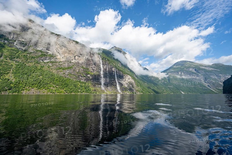 Atmospheric fjord landscape with waterfall The Seven Sisters, Geirangerfjord with reflection, Møre og Romsdal, Norway, Europe