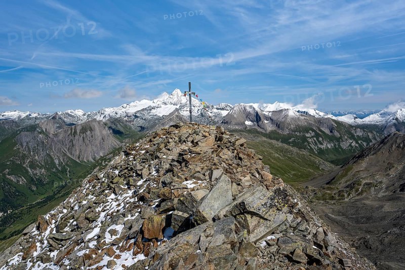 Böses Weibl summit with summit cross and colourful prayer flags, view of picturesque mountain landscape with snow-covered summit of the Großglockner, Wiener Höhenweg, Schober group, Hohe Tauern National Park, Carinthia, Austria, Europe