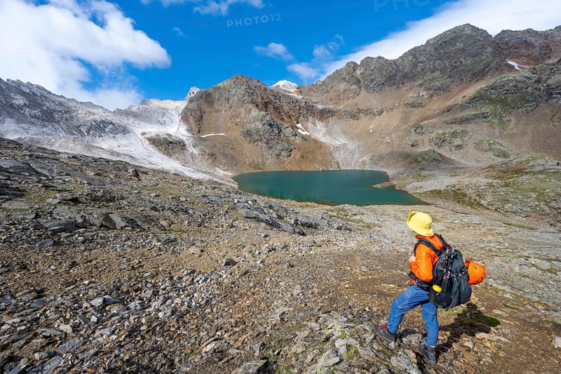 Mountaineer in front of mountain landscape with limestone rocks between granite mountains, mountain lake Hinterer Senner Egetsee and mountain peak of the Moarer Weißen, Seven Lakes Hike, Stubai Alps, near Ridnaun, South Tyrol, Italy, Europe