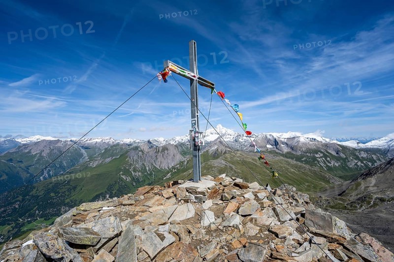 Böses Weibl summit with summit cross and colourful prayer flags, view of picturesque mountain landscape with snow-covered summit of the Großglockner, Wiener Höhenweg, Schober group, Hohe Tauern National Park, Carinthia, Austria, Europe