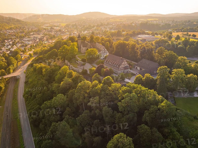 A village view from above with church and half-timbered houses on a tree-covered hill, event and wedding location Lorch Monastery, Lorch, Germany, Europe