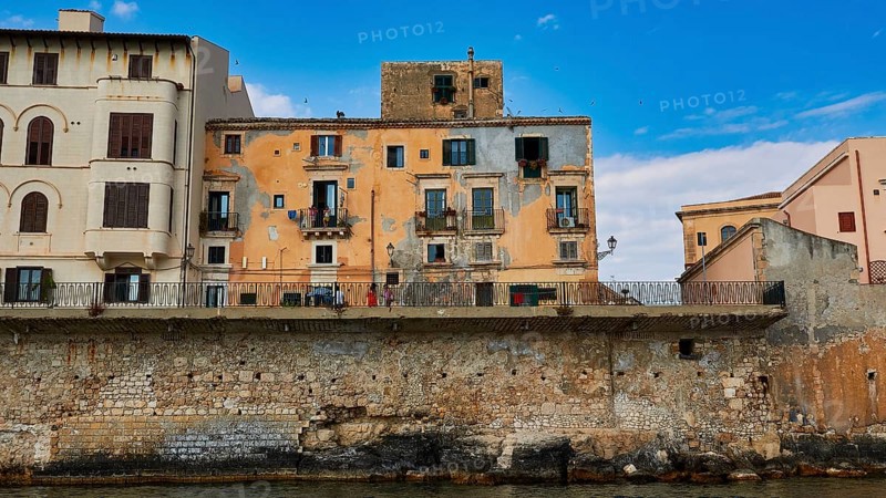 Houses with colourful facades and balconies along a stone seawall, boat trip around the island of Ortigia, Isola di Ortigia, Syracuse, Sicily, Italy, Europe