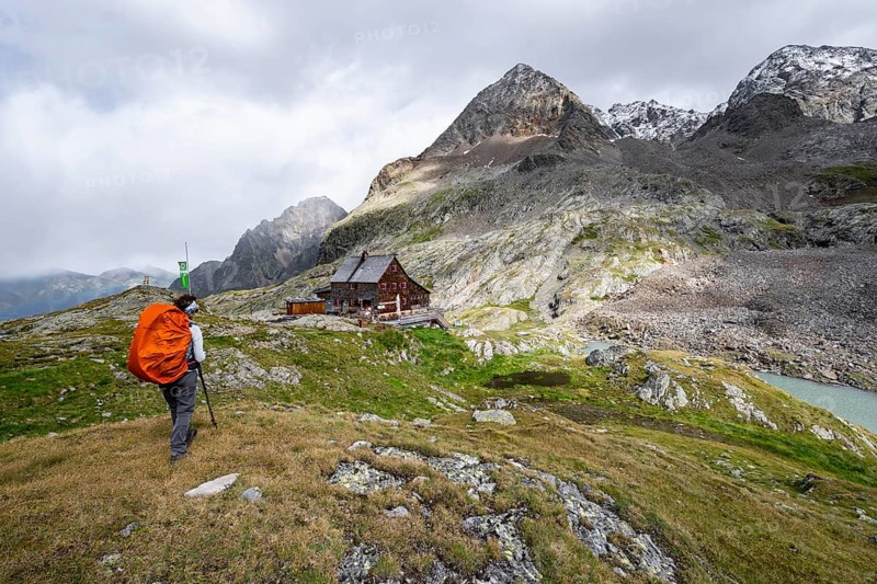 Mountaineer in front of mountain hut Adolf-Nossberger-Hütte, mountain landscape with rocky mountain peaks, in the background summit of Petzeck and Kruckelkopf, Schober group, Hohe Tauern National Park, Carinthia, Austria, Europe