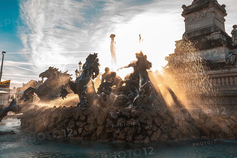 The majestic monument aux girondins fountain, located in place des quinconces, bordeaux, is illuminated by the golden rays of the setting sun