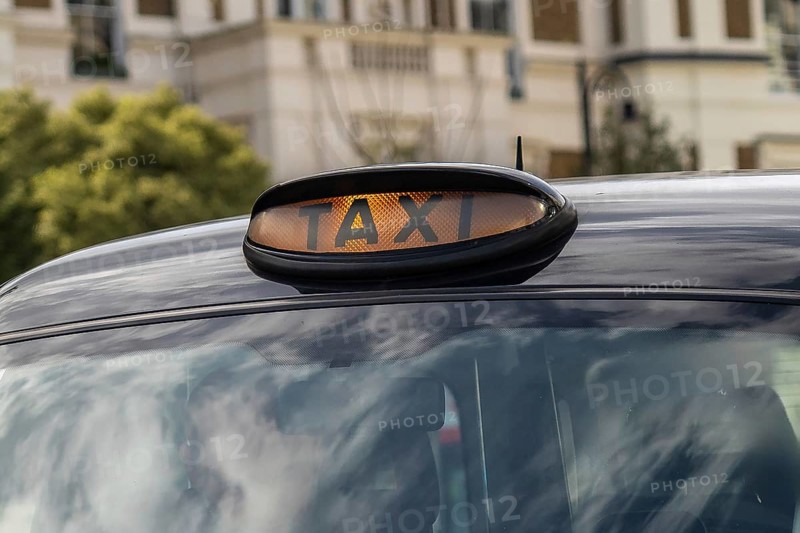 Illuminated taxi sign on top of a classic black cab in london, england, providing transportation services in the urban environment
