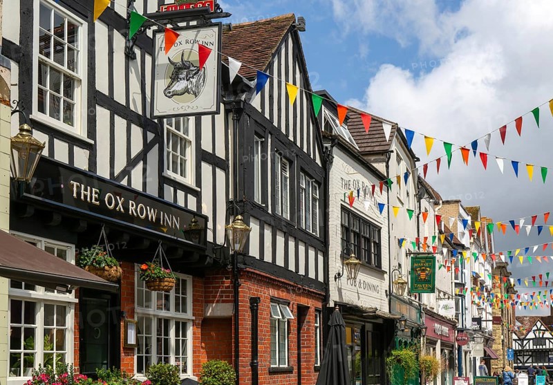 Bunting flags decorating buildings in historic street, The Ox Row Inn and shops, Butcher Row, Salisbury, Wiltshire, England, UK
