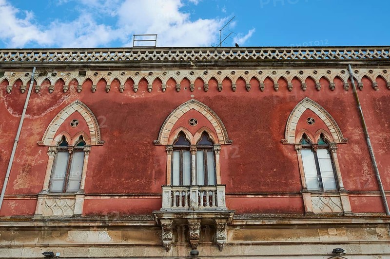 Red façade of a building with Gothic windows and decorative details, Ortigia Island, Isola di Ortigia, Historic Centre, Syracuse, Sicily, Italy, Europe