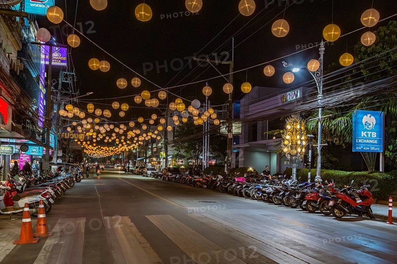 Scooters and motorcycles under lighted spheres strung across downtown street in Chiang Rai, Thailand, Asia