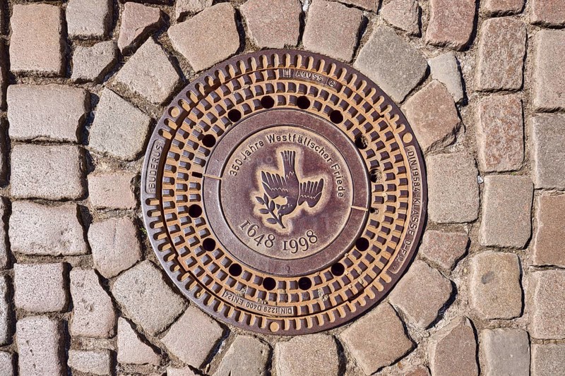 Manhole cover, dove of peace, 350 years of the Peace of Westphalia, 1648 to 1998, biblical symbol, cobblestones, Münster, Münsterland, independent city, North Rhine-Westphalia, Germany, Europe