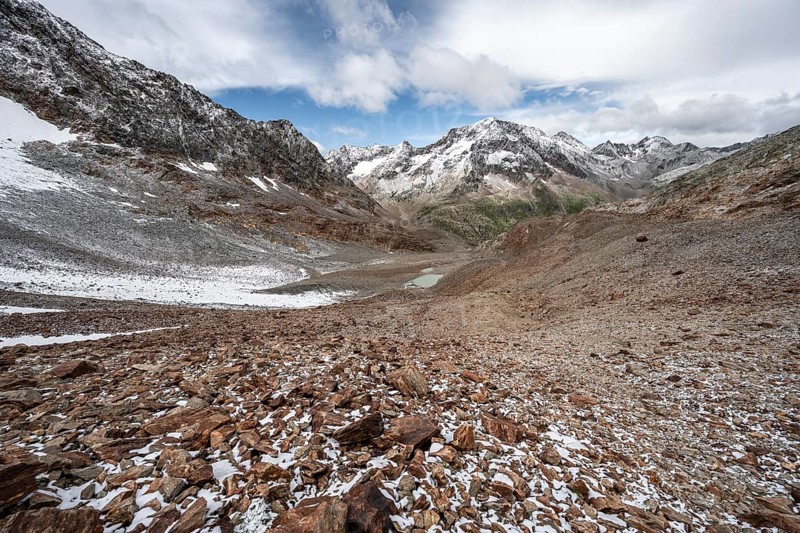 View of steep rocky mountain landscape with fresh snow in summer, descent from the Hornscharte, on the Wiener Höhenweg, behind summit Roter Knopf, Schober group, Hohe Tauern National Park, Carinthia, Austria, Europe