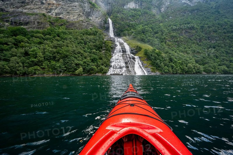 Kayak trip on the Geirangerfjord at the Freier waterfall, tip of a red kayak in the fjord, atmospheric fjord landscape, first person view, near Geiranger, Møre og Romsdal, Norway, Europe