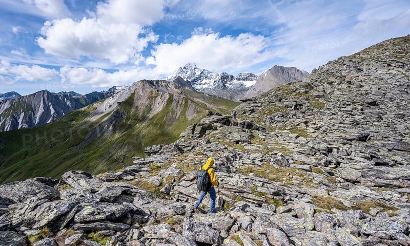 Mountaineer in boulder terrain, at the summit of Kastenegg, view of picturesque mountain landscape with snow-covered summit of the Großglockner, Vienna High Mountain Trail, Schober Group, Hohe Tauern National Park, Carinthia, Austria, Europe