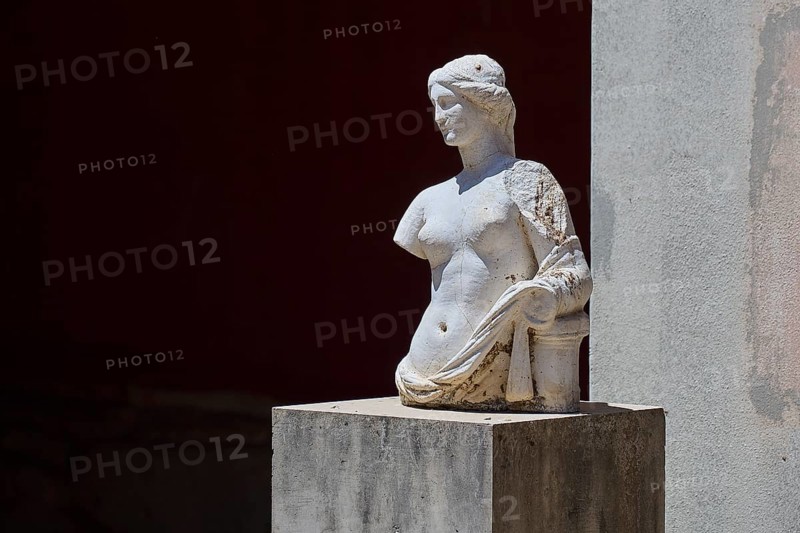 ©Udo Rein, An ancient marble bust with damaged arms stands on a pedestal in the shade, Aphrodite, Casa Romana, Kos Town, Kos, Dodecanese, Greek Islands, Greece, Europe