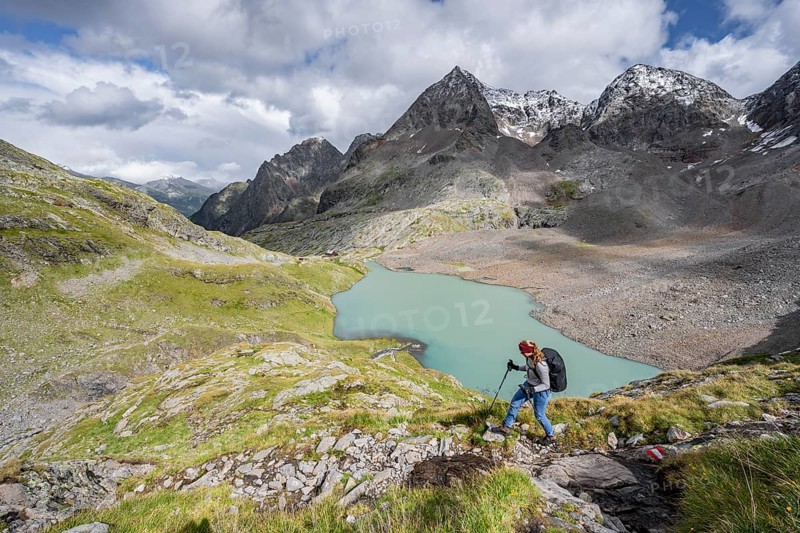 Mountaineer on hiking trail in mountain landscape, view of turquoise-blue mountain lake Großer Gradensee, behind summit of Petzeck and Kruckelkopf, Schober group, Hohe Tauern National Park, Carinthia, Austria, Europe