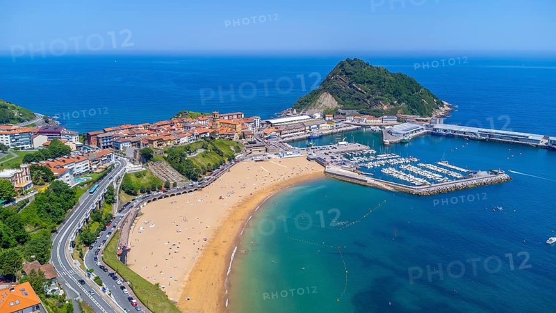 Aerial view of getaria, a charming coastal town in the basque country, spain, showcasing its picturesque harbor, sandy beach, and the iconic mount san anton on a sunny summer day