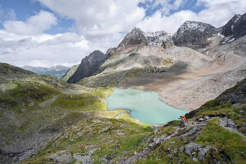Mountaineer on hiking trail, view of turquoise-blue mountain lake Großer Gradensee, behind summit of Petzeck and Kruckelkopf, Schober group, Hohe Tauern National Park, Carinthia, Austria, Europe