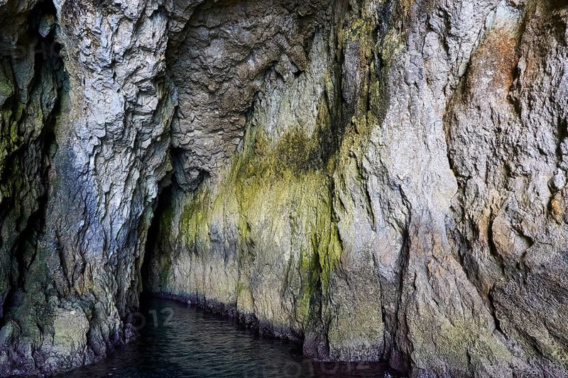 Entrance to a dark cave with irregular rock structures, boat trip around the island of Ortigia, Isola di Ortigia, Syracuse, Sicily, Italy, Europe