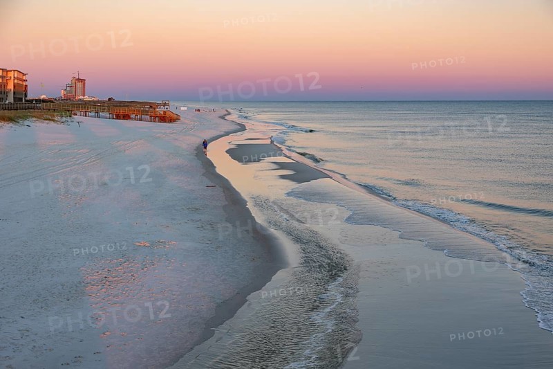 Woman and child walking along the Gulf of Mexico beach as the sun rises over the Gulf of Mexico at Gulf Shores, Alabama