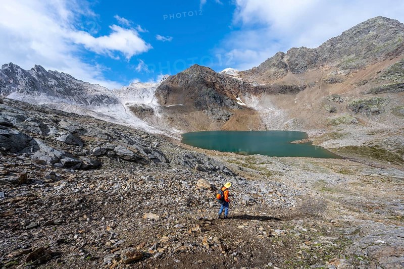 Mountaineer on a hiking trail, mountain landscape with limestone rocks between granite mountains, mountain lake Hinterer Senner Egetsee and mountain peak of the Moarer Weißen, Seven Lakes Hike, Stubai Alps, near Ridnaun, South Tyrol, Italy, Europe