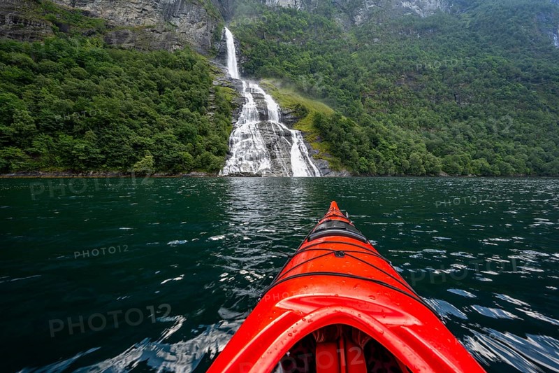 Kayak trip on the Geirangerfjord at the Freier waterfall, tip of a red kayak in the fjord, atmospheric fjord landscape, first person view, near Geiranger, Møre og Romsdal, Norway, Europe
