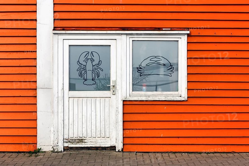 Colourful lobster shack, orange wooden façade with door and window, lobster pictogram, façade detail in the harbour, Heligoland, Schleswig-Holstein, Germany, Europe