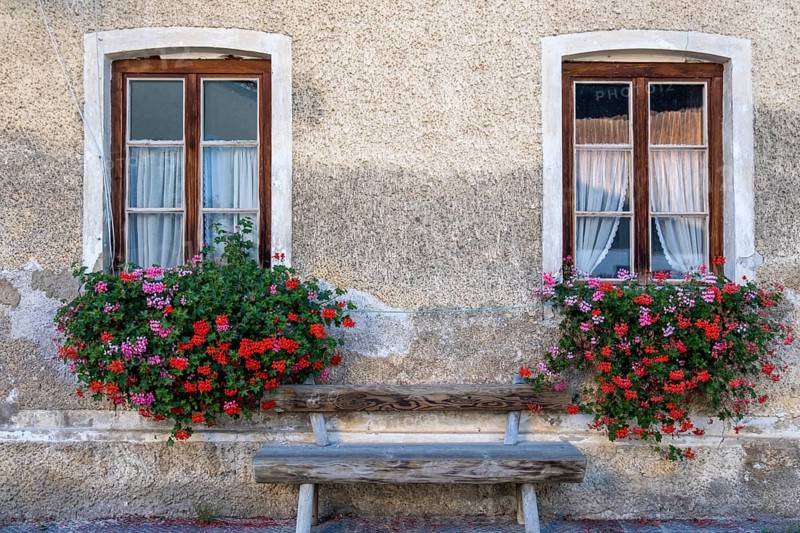 Two windows with flower boxes and wooden bench on a charming stone wall, Umrathshausen, Bavaria, Germany, Europe