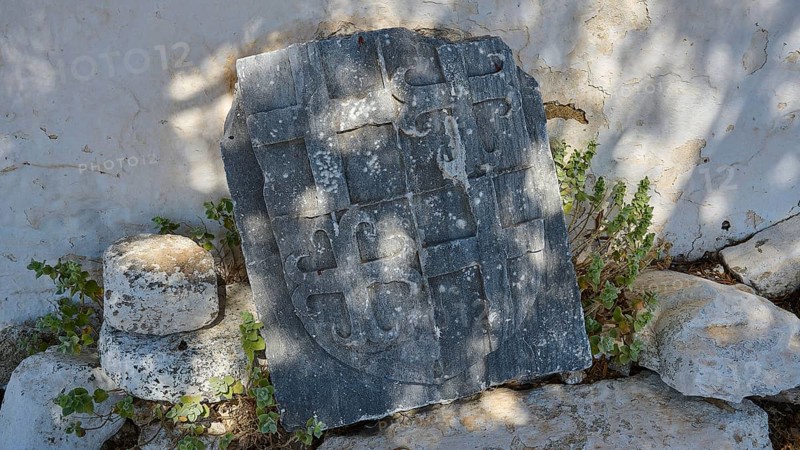 Ancient tombstone with inscriptions, surrounded by vegetation and shade, Church of Agia Paraskevi, Antimacheia, Medieval Fortress, St John's Fortress, Antimachia, Kos, Dodecanese, Greek Islands, Greece, Europe
