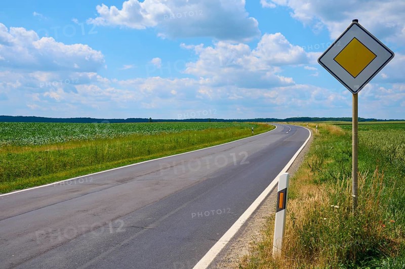 Empty, winding road with traffic sign and wide sky with clouds, Hausen, Würzburg district, Mainfranken, Bavaria, Germany, Europe