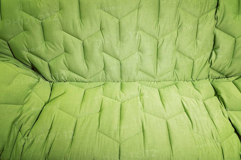 Close-up comfortable green soft sofa with curly stitching. Modern design