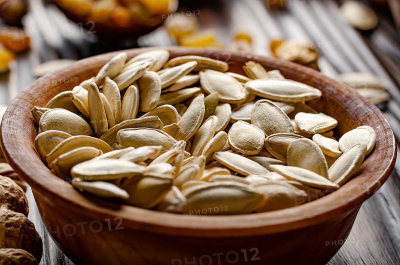 Pumpkin seeds in wooden bowl on kitchen table food background