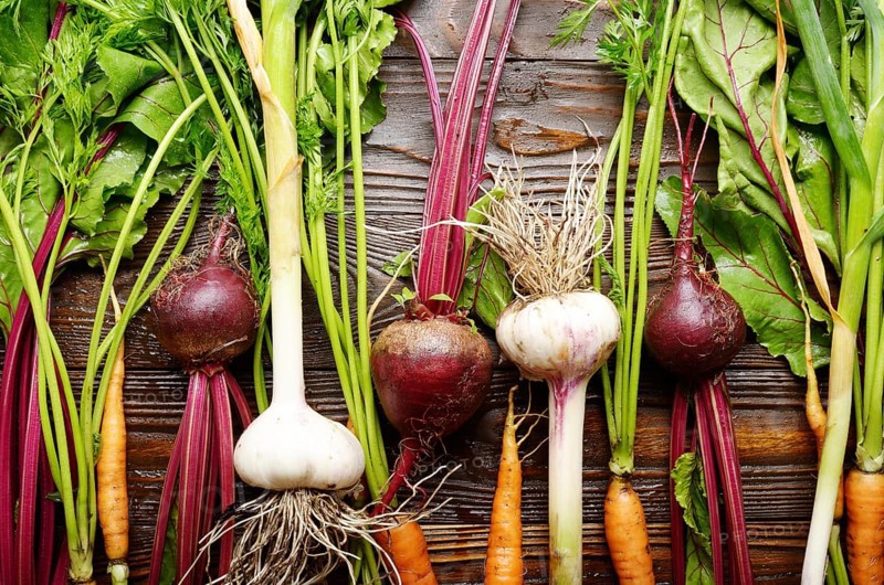 Vegetarian background of fresh organic beetroots green garlic and carrots on kitchen wooden rustic table