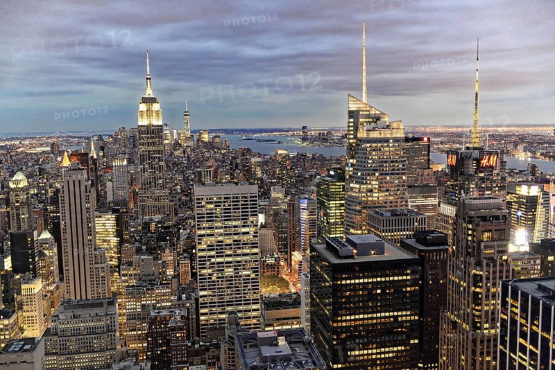 Rockefeller Center observation deck, panoramic view of the dense New York City skyline, skyscrapers are illuminated in the evening skyline under a cloudy sky, Manhattan, New York City, New York, USA, North America
