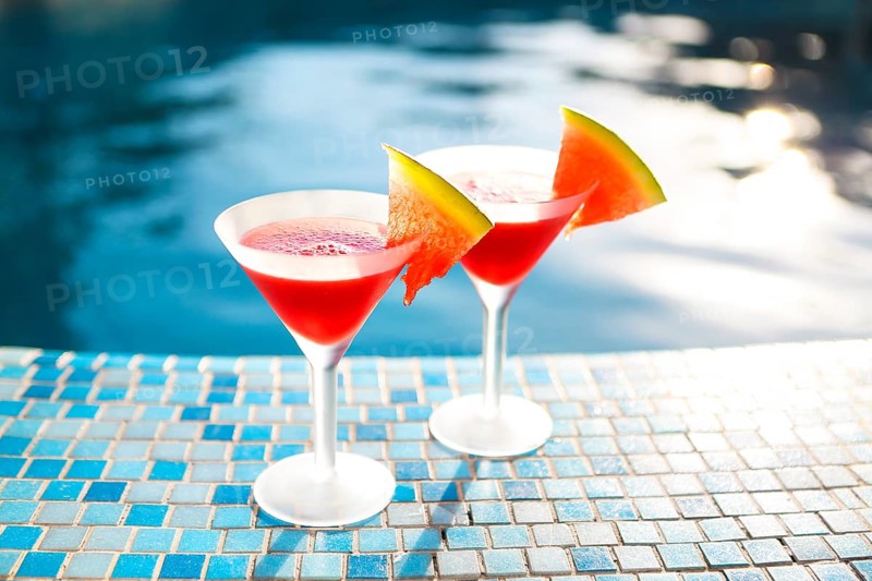 Glasses of watermelon cocktail with watermelon slices near the pool