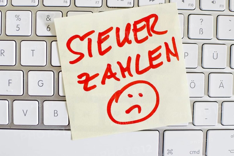 A note on the keyboard of a computer as a reminder: Pay tax Austria