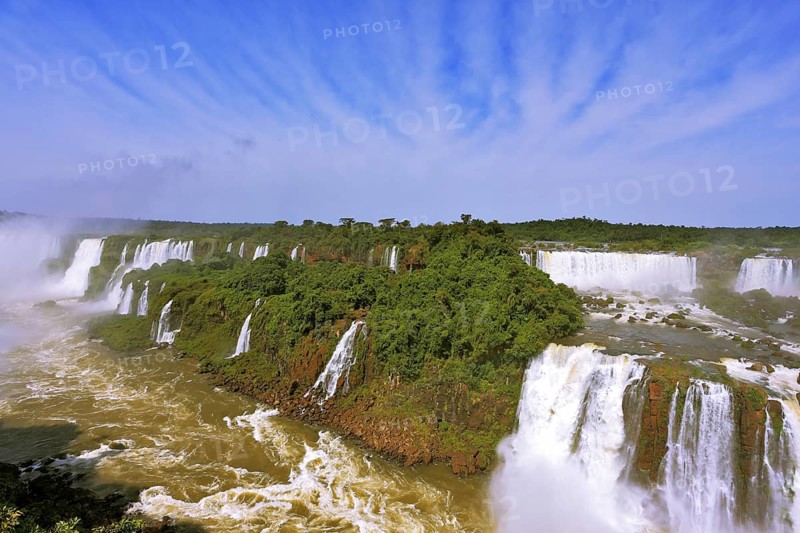 Roaring falls in South America - Iguazu. Foamy streams fall between the green jungle. The magnificent rainbow is shone in a water dust