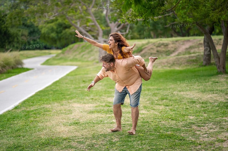 Man giving his girlfriend a piggyback ride in a park
