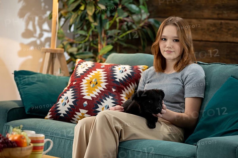 A young woman happily enjoys quality time with her adorable puppy in a stylish and inviting living room setting