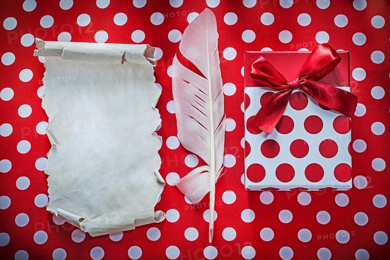 Present box vintage sheet of paper plume on polka-dot red table cloth celebrations concept