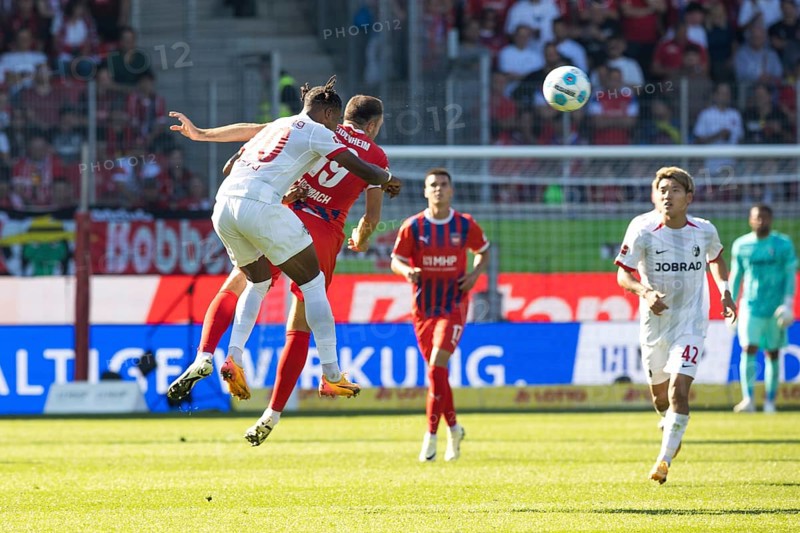 Football match, Junior ADAMU SC Freiburg left and Jonas FÖHRENBACH 1. FC Heidenheim in aerial combat for the ball, Ritsu DOAN SC Freiburg on the right, Voith-Arena football stadium, Heidenheim