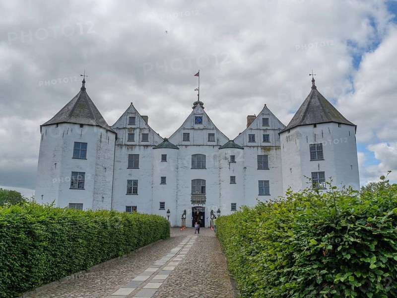 An impressive white castle with several turrets under a cloudy sky, glücksburg, schleswig-holstein, germany