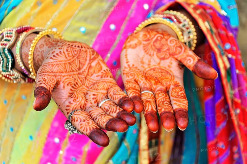 Close-up of painted hands with elaborate mehndi designs, accompanied by colourful robes, Rajasthan, North India, India, Asia