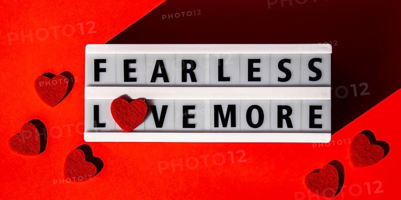 Lightbox with text FEAR LESS LOVE MORE. Motivational Words Quotes Concept with red hearts. Colorful red background. Minimalistic creative concept. Inspirational phrase